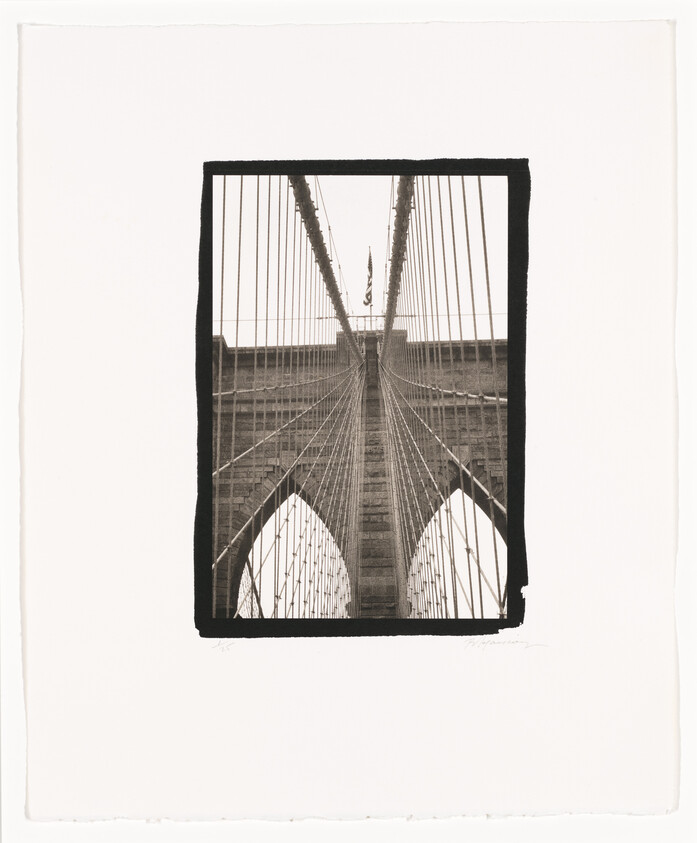 Brooklyn Bridge stone tower and radiating suspension cables converging toward an American flag at the top.