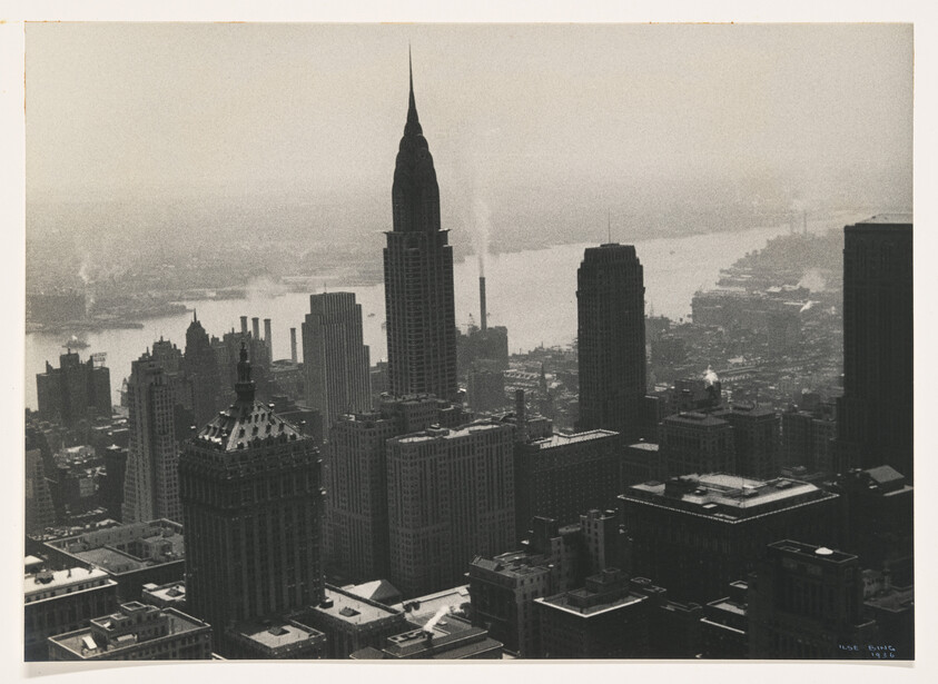 New York skyline dominated by the Chrysler Building rising above other Midtown skyscrapers with the river beyond.