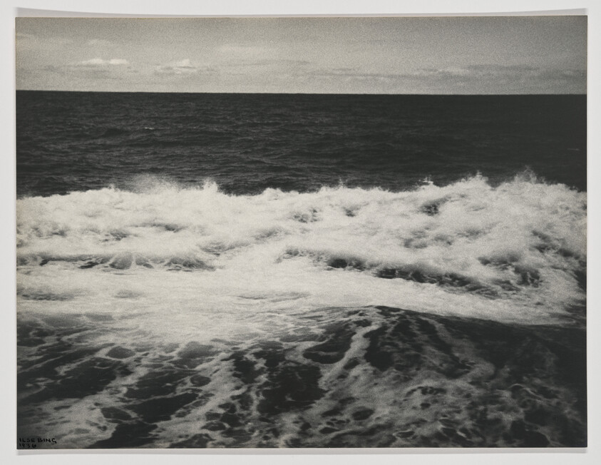 Rough ocean waves breaking toward the shore under a cloudy, low horizon.