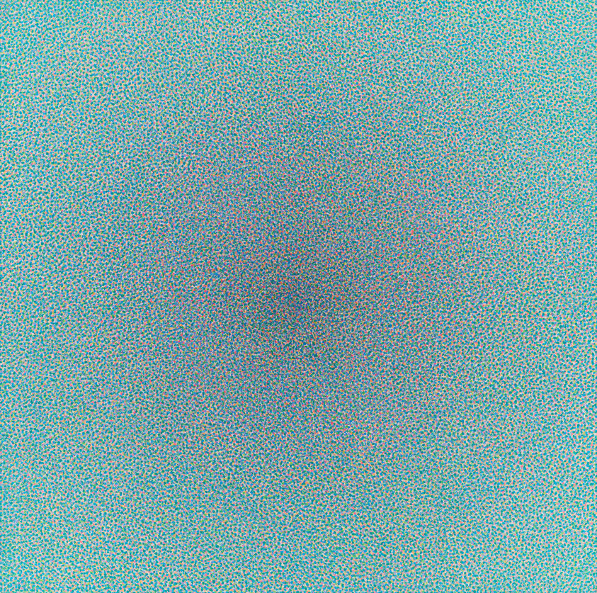 A field of tiny colorful dots forming a subtle darker circular blur in the center.