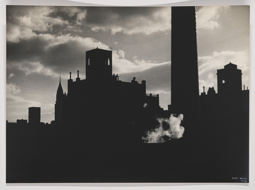 Dark city skyline silhouettes against a cloudy sky with steam rising from a rooftop.