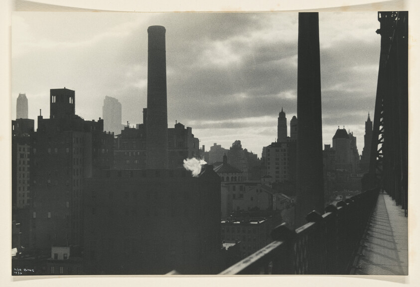 City skyline with tall smokestacks and a small plume of smoke rising near the center.