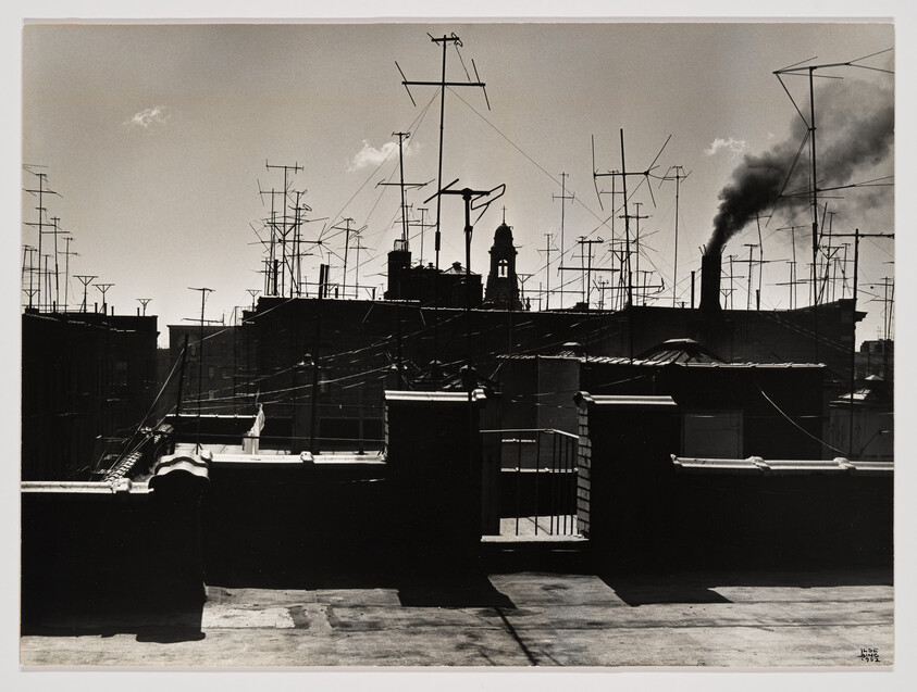 Rooftop skyline filled with dozens of TV antennas and a smokestack blowing dark smoke.