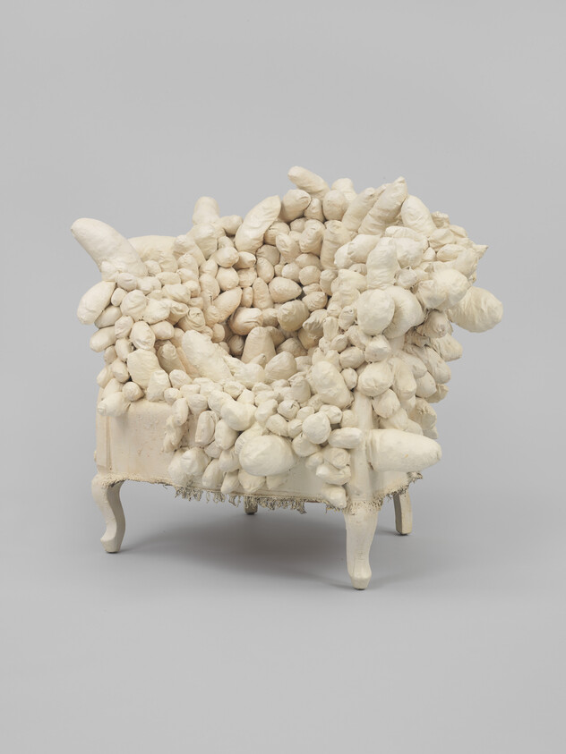 An ivory armchair engulfed in soft globular shapes.