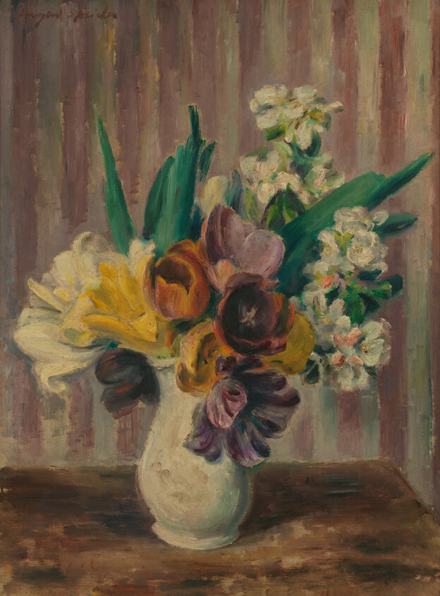 A white vase holds a colorful bouquet of tulips and other flowers on a wooden table.