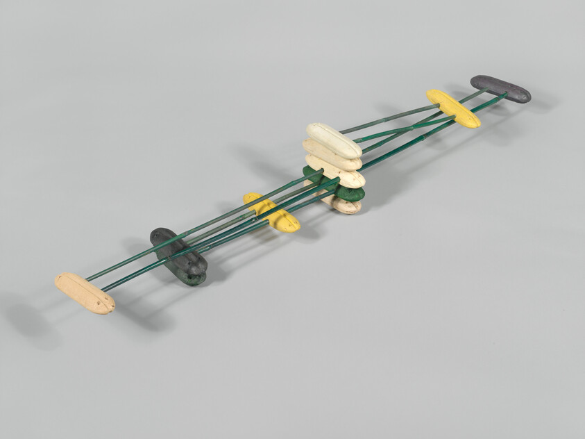 Long green metal frame with yellow, white, and gray oval floats threaded along its rods.