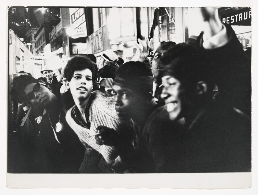A crowd of young people leaning toward the camera on a busy city street at night.