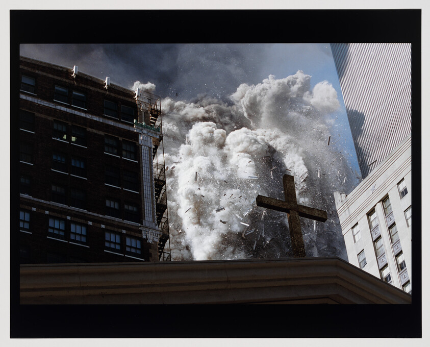 A church rooftop cross stands as a massive cloud of dust and debris explodes between nearby buildings.