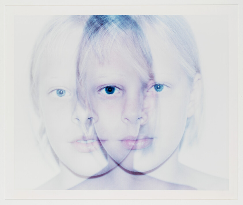 Young child's face duplicated three times in a blurred, overlapping portrait with bright blue eyes.