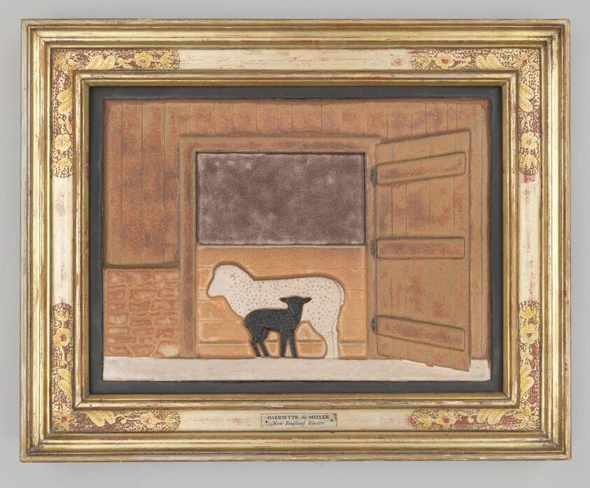 A framed folk-art scene of a white sheep and black lamb standing inside a barn stall.