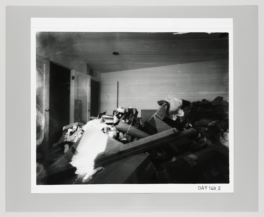 A cluttered room filled with a large pile of discarded furniture, boxes, and debris.