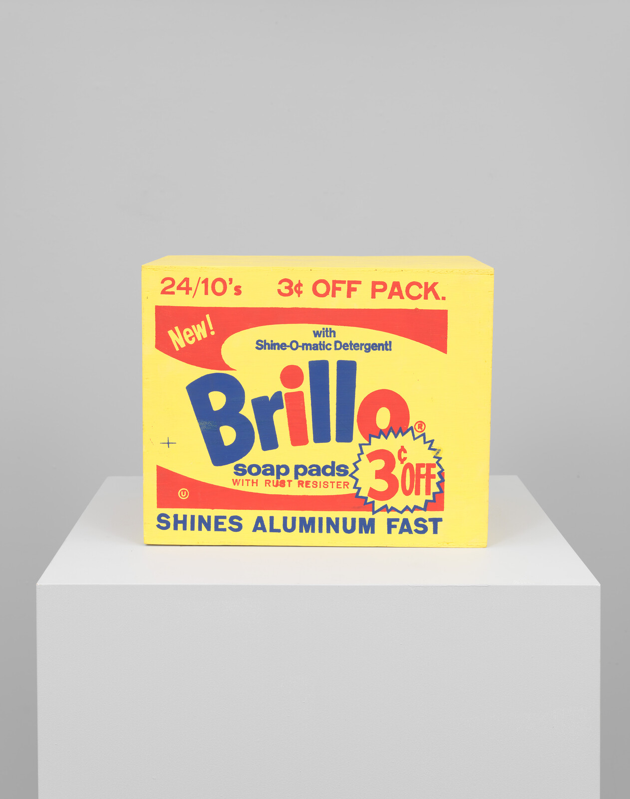 Yellow Brillo soap pads box with red and blue text, offering 3¢ off. Promises to shine aluminum fast. Placed on a white pedestal.
