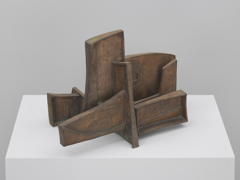 Abstract bronze sculpture of intersecting curved panels arranged on a white pedestal.