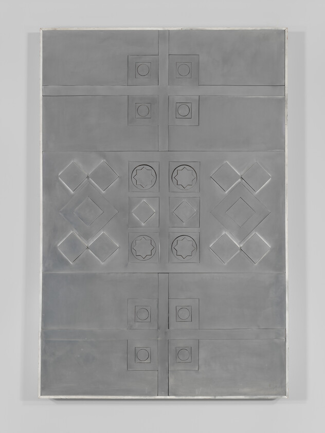 A large metal panel with symmetrical embossed geometric shapes including squares, diamonds, and star motifs.