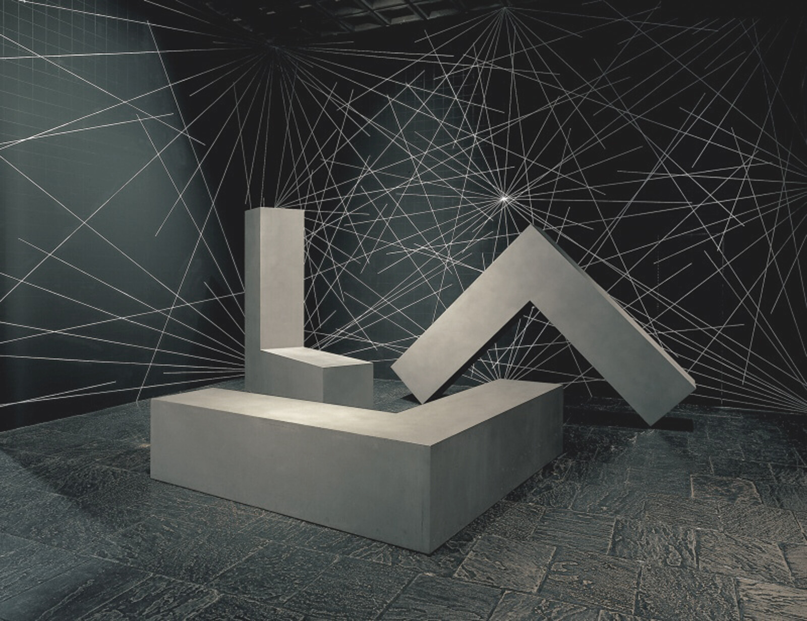 Geometric shapes installation with a complex web of white lines on a dark background.
