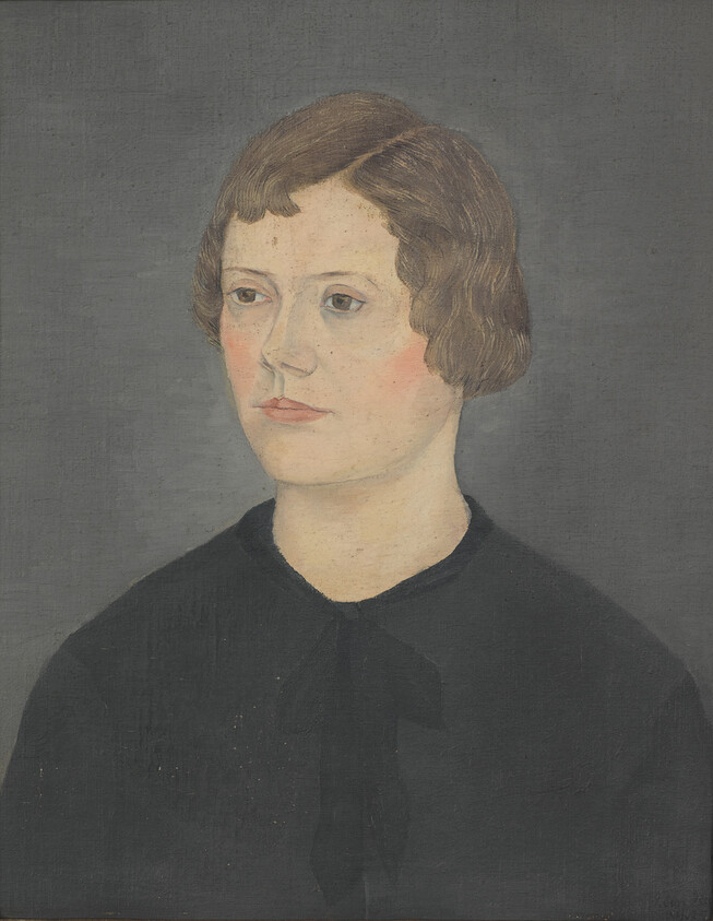 Young person with short brown hair and dark clothing looking slightly to the left with a neutral expression.
