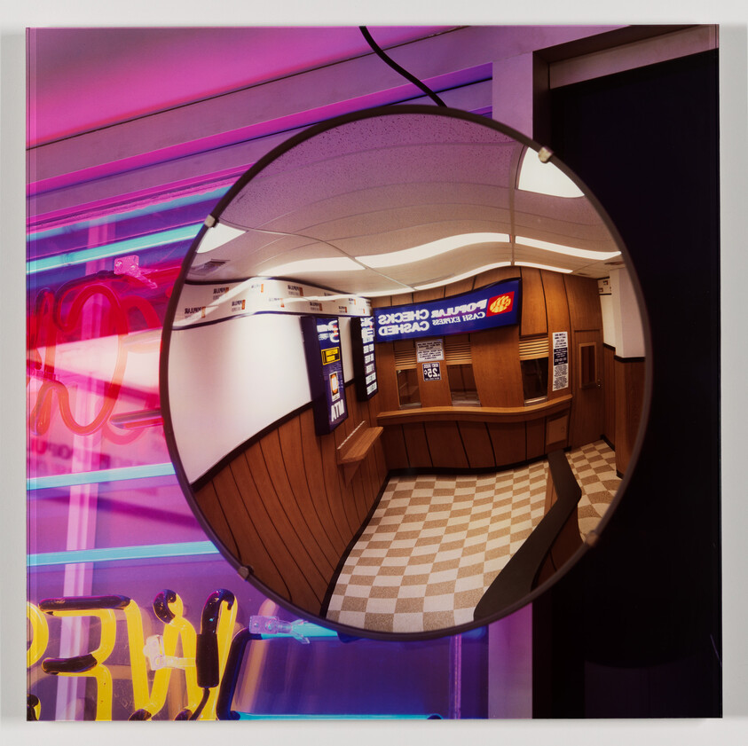 A convex security mirror reflects an interior space with neon lights and a checkered floor.