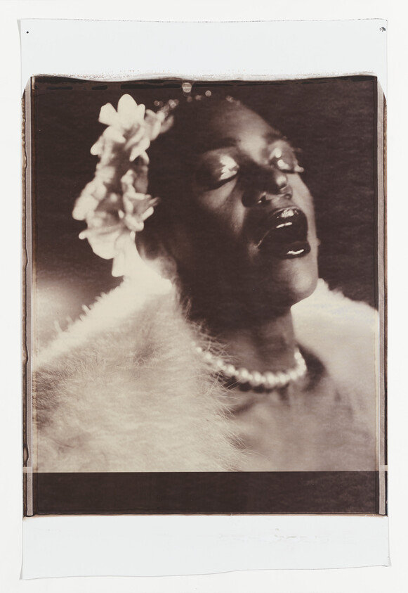 A woman sings with closed eyes, wearing a flower headpiece, pearl necklace, and fur stole.