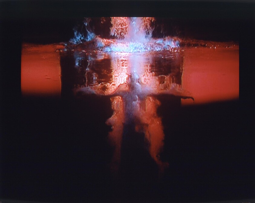 A powerful underwater explosion creates a vertical plume and glowing red-blue water disturbance.