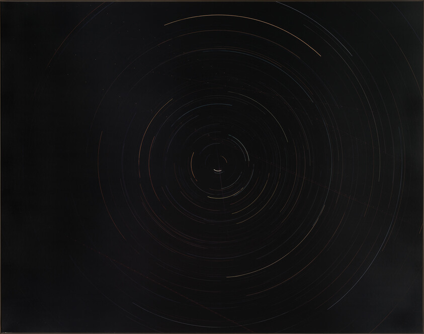 Long-exposure star trails form concentric circles around the North Star in a dark night sky.