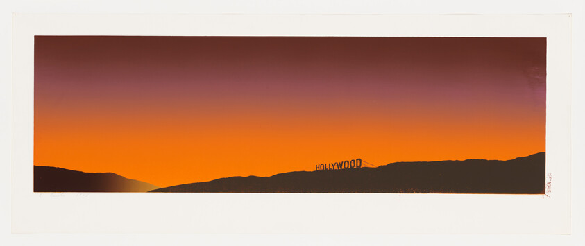 Distant Hollywood sign on a dark hillside against a wide orange and purple sunset sky.