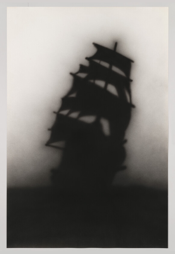 A dark silhouetted tall ship with multiple sails looms above a blurred horizon.