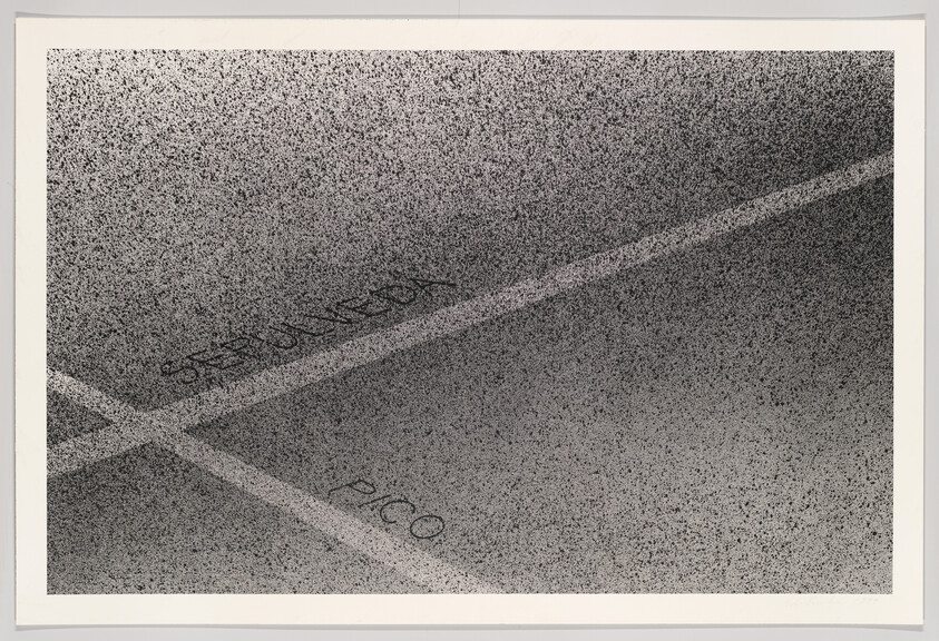 Parking lot pavement with painted lines and faded words reserved and pico.