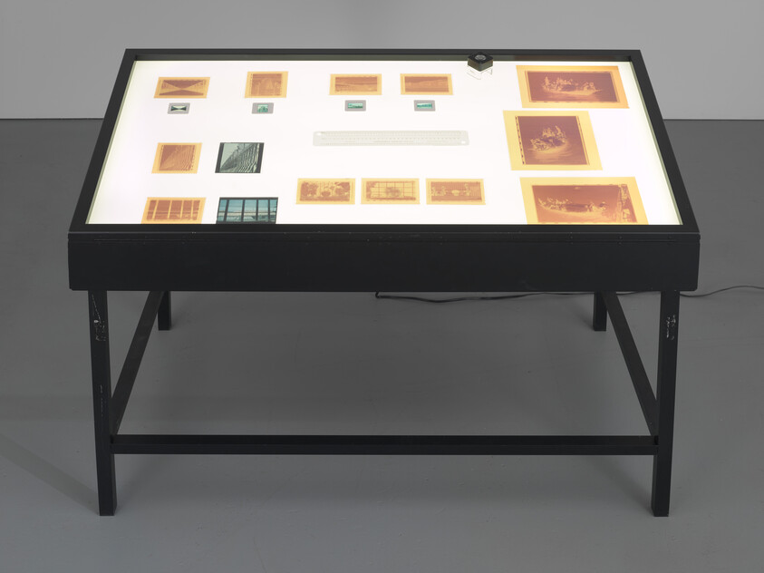 Light table with arranged photographic negatives and slides displayed under a glass surface.