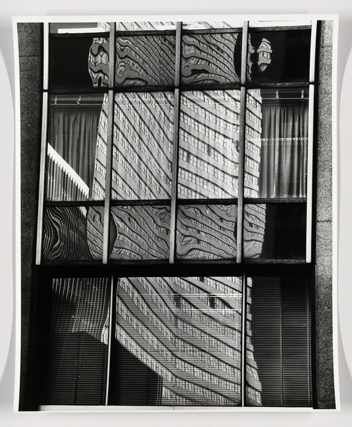 Glass windows reflecting a distorted skyscraper with wavy patterns across the panes.