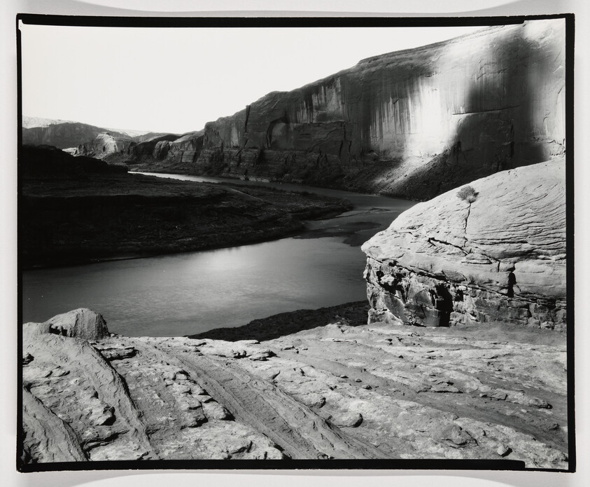 A river winds through a deep canyon with steep sandstone cliffs and rocky foreground.