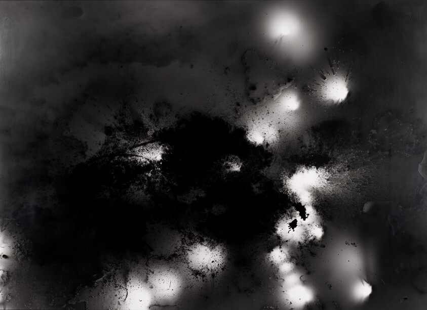 Dark ink blots spread across the surface with scattered bright white splatters and glowing spots.