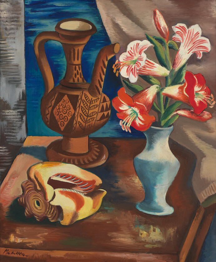 A blue vase holding red and white amaryllis beside a carved brown pitcher and shell.