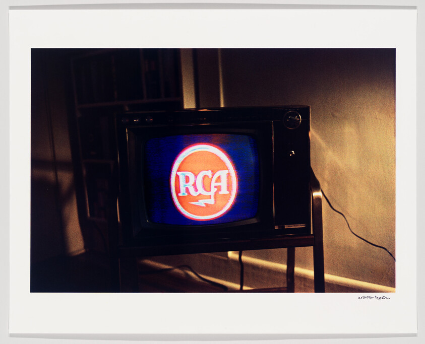 Old television set on a stand displaying a glowing red RCA logo on the screen.