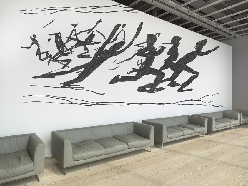 Large wall mural of black silhouetted figures running above a row of gray sofas.