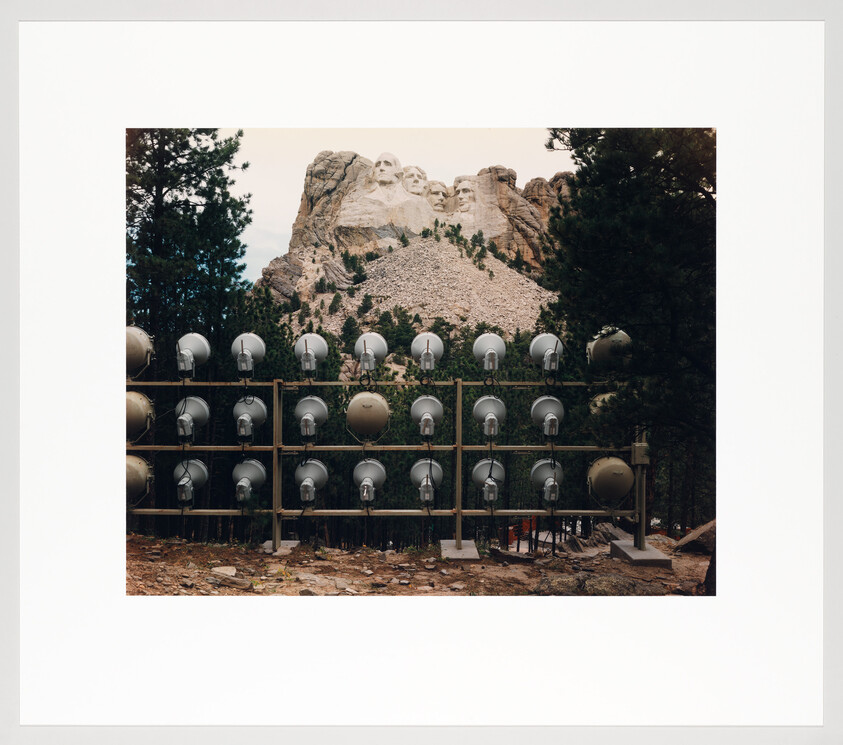 Mount Rushmore seen behind a large scaffold of parade-style spotlights set up in front.