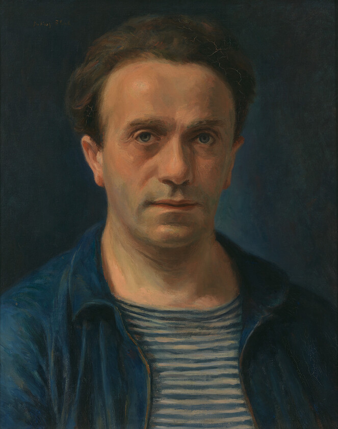 A serious-looking man wearing a blue jacket and striped shirt against a dark background.