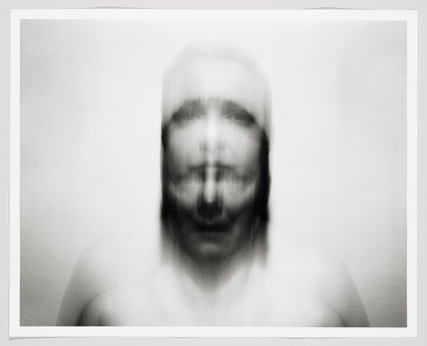 A blurred black-and-white portrait shows a face multiplied by vertical motion and soft ghosting.