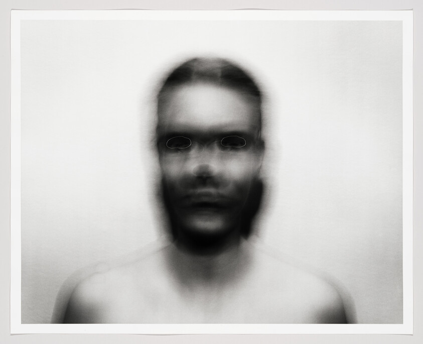Blurry double-exposed portrait of a shirtless person with ghostlike overlapping facial features.