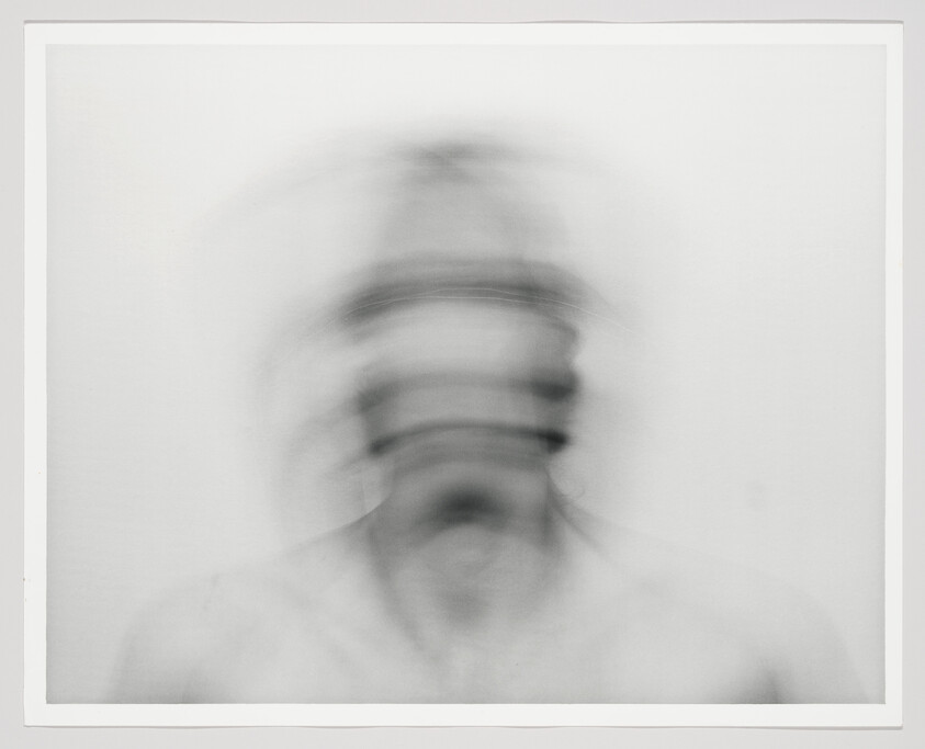 A blurred head turning rapidly creating layered, ghost-like facial outlines.