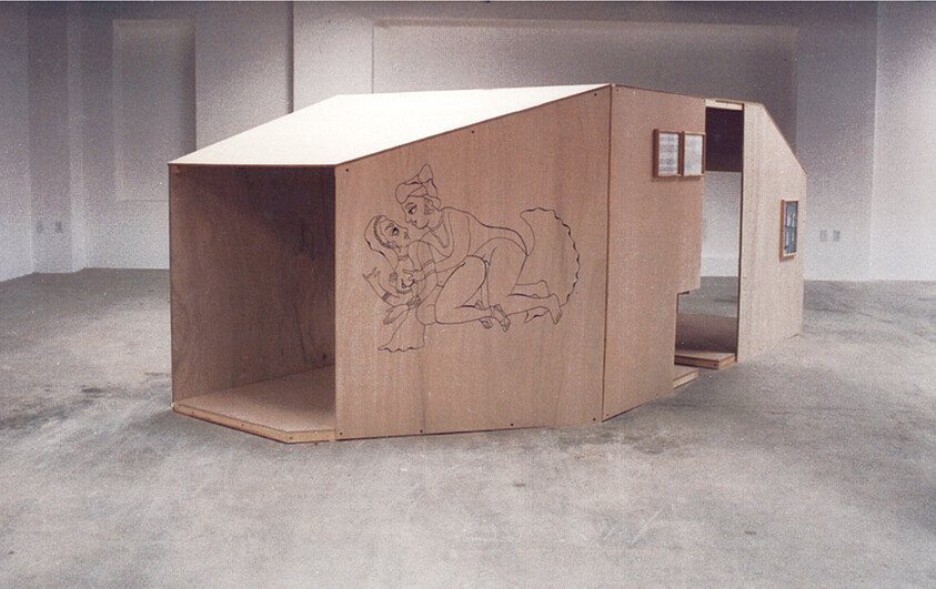 A large plywood playhouse structure in an empty gallery with a line drawing of two figures.