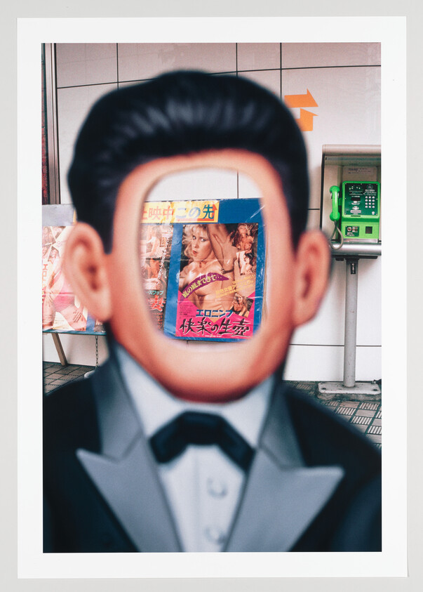 Cutout standee of a man in a tuxedo with a face-shaped hole revealing a poster behind.