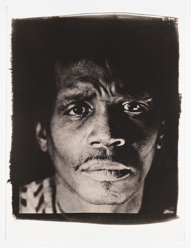 A brown monochrome portrait of a Black man with furrowed brows.