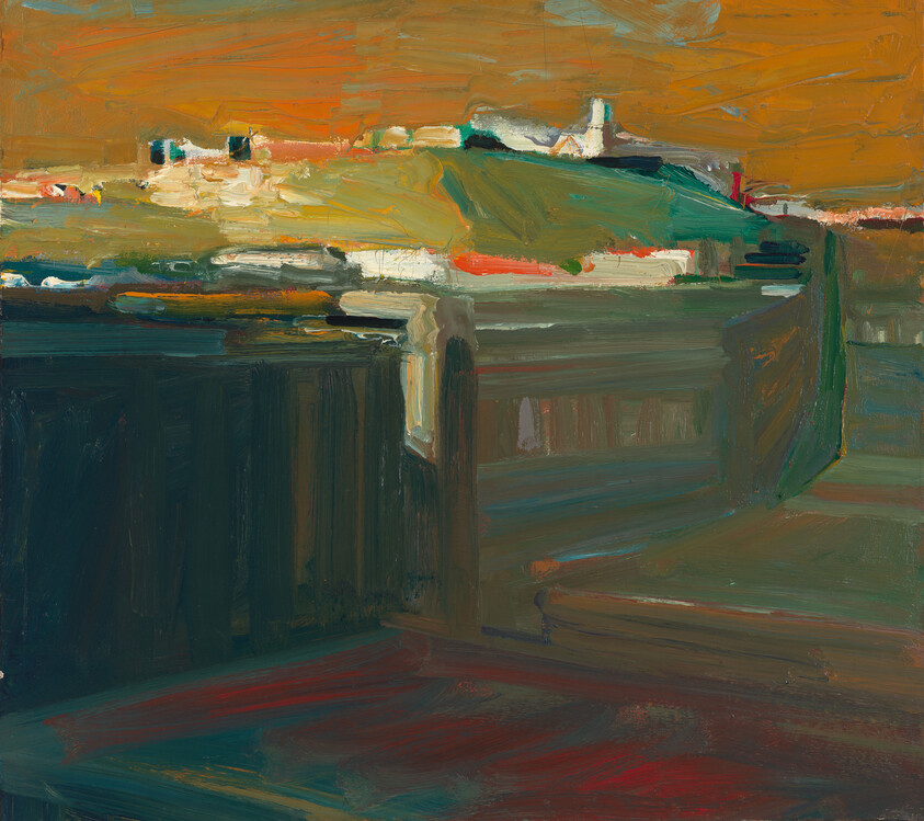 A dark wooden railing overlooks a distant green hill with a small white building under an orange sky.