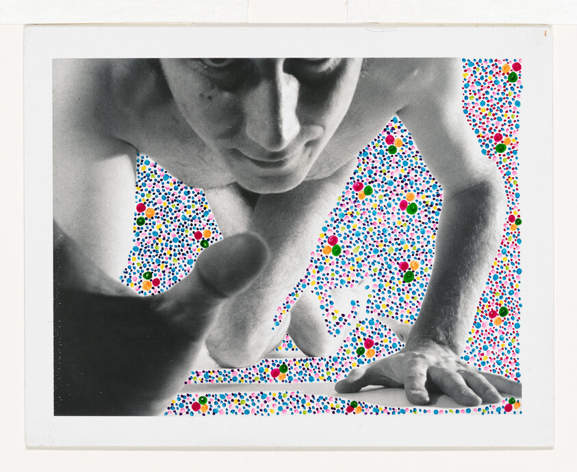 A shirtless person reaches forward over a colorful polka-dot background.