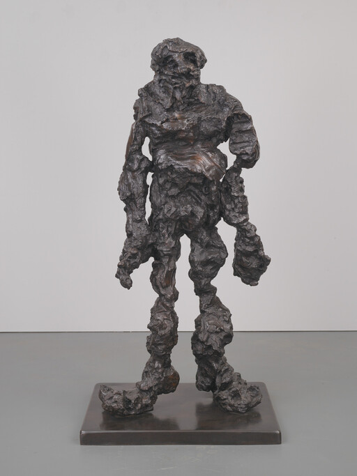 Rough-textured bronze sculpture of a standing human-like figure with distorted limbs on a base.