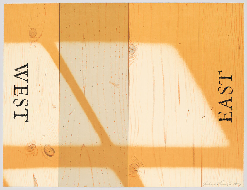 Wooden planks painted with orange shadow shapes and the words West and East stenciled vertically.