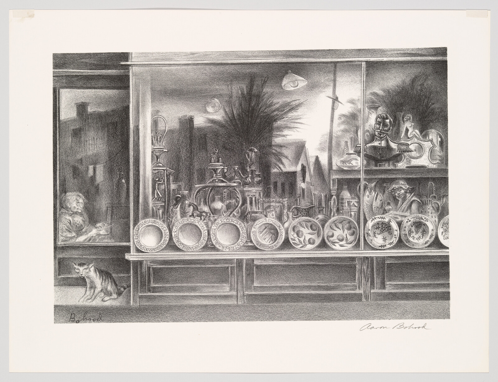 A shop window display of decorative plates and ceramics with a cat sitting by the storefront.