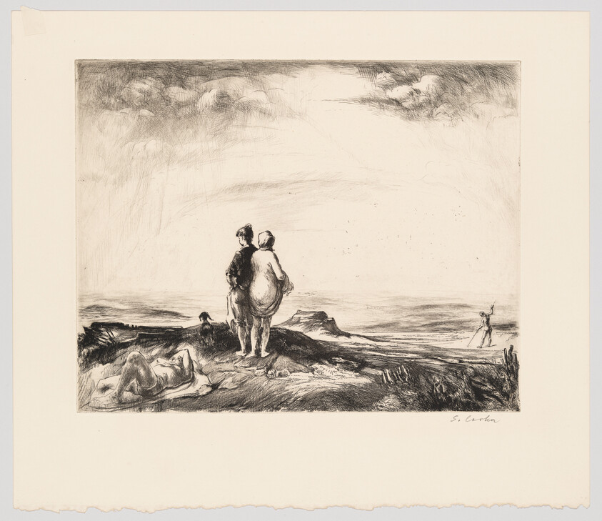 Two people stand on a rocky shore looking out to sea while others rest nearby.