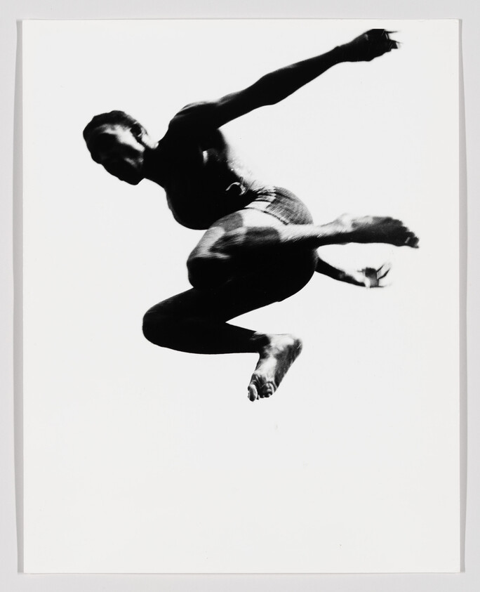 A person captured mid-air in a dynamic tuck jump with arms and legs bent.