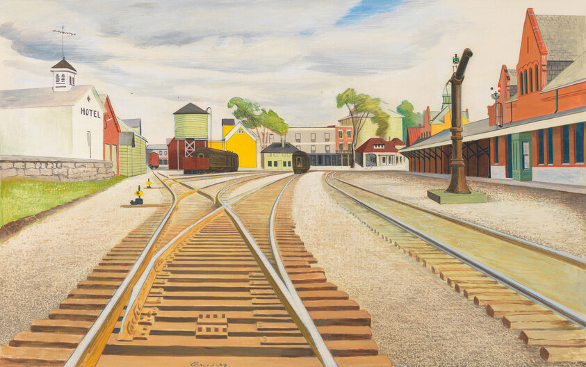 Train tracks fan out into a small town of brightly colored buildings on a cloudy day